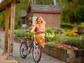 woman in orange dress walks bikes past garden